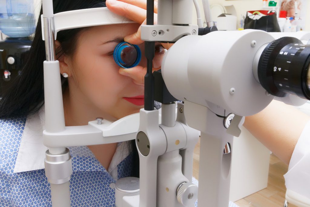 Funduskopie an der Spaltlampe einer jungen Frau mit indirekter Ophthalmoskopie
